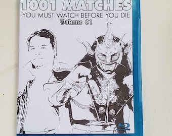 May include: A blue Blu-ray disc case with the title "1001 Matches You Must Watch Before You Die Volume 01". The cover features a black and white illustration of a masked wrestler and a man.