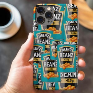 May include: A phone case with a repeating pattern of Heinz Beanz cans. The cans are blue and black with white text and feature a variety of beans. The text on the cans reads "Heinz Beanz 415g".