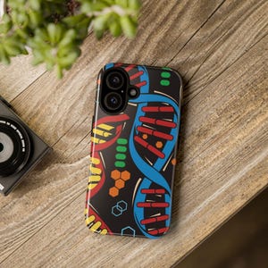 May include: A black smartphone case with a vibrant DNA double helix pattern. The design incorporates red, yellow, blue, and orange shapes. The case is set against a wooden background.