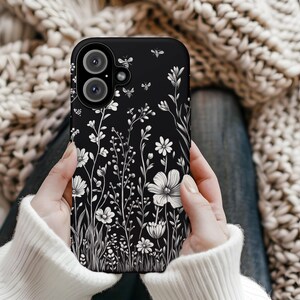 May include: Black phone case with a white floral design and small bee silhouettes.
