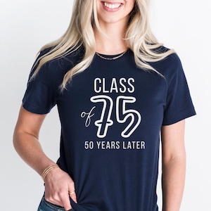 Könnte beinhalten: Marineblaues T-Shirt mit dem weißen Text "CLASS of '75 50 YEARS LATER". Das T-Shirt hat einen Rundhalsausschnitt und scheint aus einem weichen Material zu sein. Das T-Shirt wird von einer Person getragen.