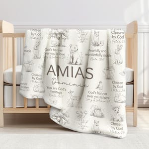 May include: A personalised baby blanket in a soft, neutral colour scheme. The blanket features a repeating pattern of sketched animals and botanical elements. The name "AMIAS" and "Dominic" are displayed, along with inspirational text.