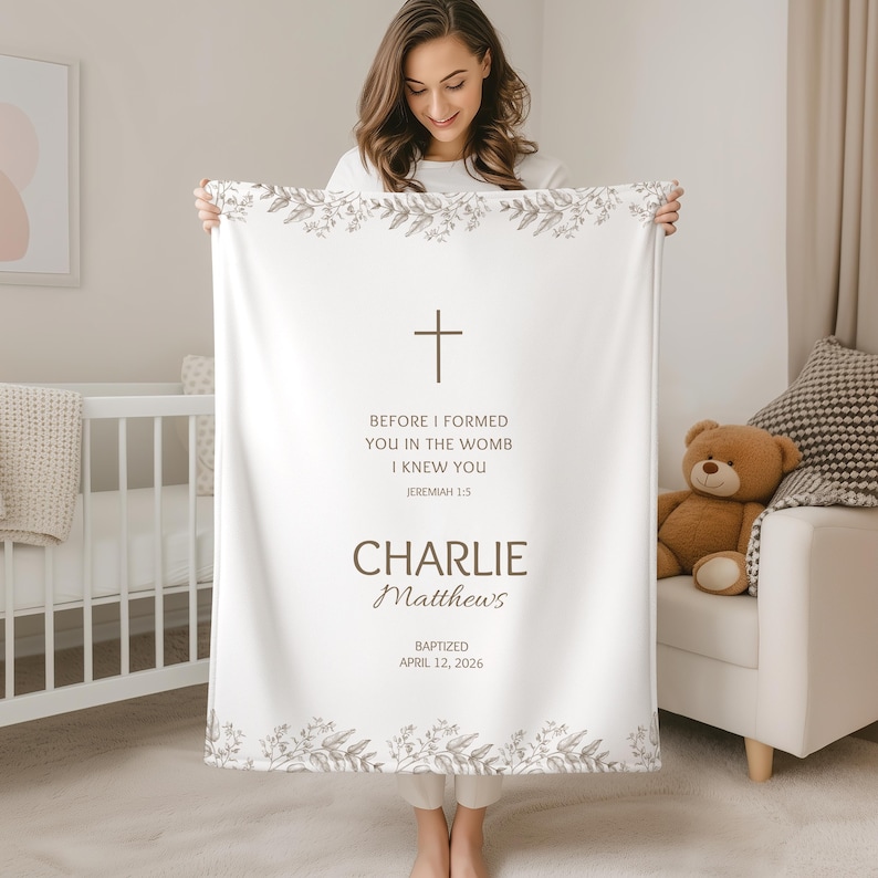 May include: A white baby blanket with a cross and floral design. The blanket has the text "BEFORE I FORMED YOU IN THE WOMB I KNEW YOU" and the name "CHARLIE".
