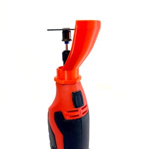 May include: A red and black rotary tool with an orange attachment and a small circular saw blade. The tool has a black grip and a red body. The orange attachment is funnel-shaped, directing debris away from the user.
