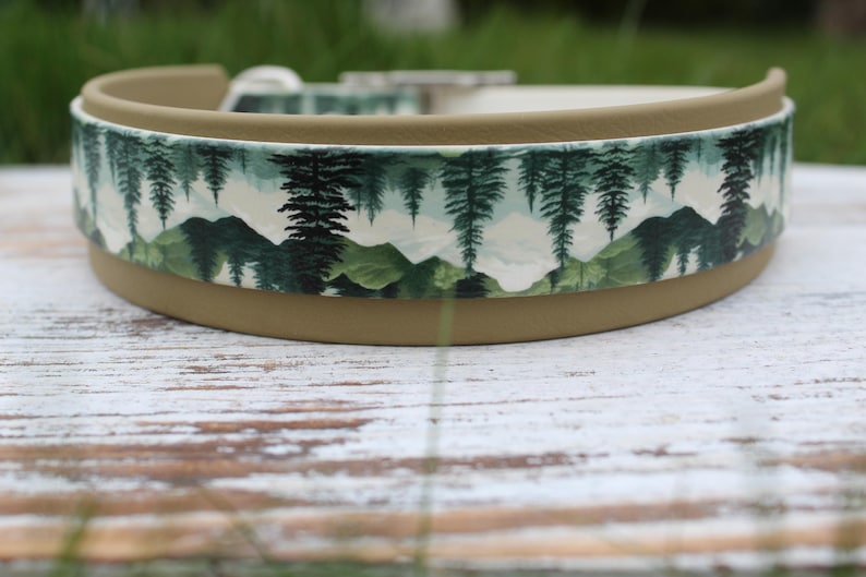 K&ouml;nnte beinhalten: Ein braunes Hundehalsband mit einem wei&szlig;en und gr&uuml;nen Berg- und Waldmuster. Das Halsband ist aus strapazierf&auml;higem Material gefertigt und hat eine robuste Schnalle.