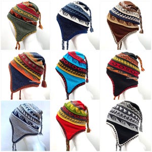 Puede incluir: Colección de nueve gorros peruanos con orejeras y diseños coloridos. Cada gorro presenta una combinación única de colores y patrones geométricos, con borlas en las orejeras. Los gorros se exhiben en una cabeza de maniquí.