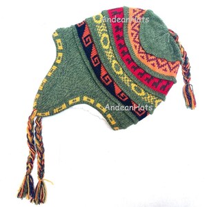 May include: A green knitted hat with ear flaps and a braided tassel. The hat features colourful geometric patterns in red, yellow, orange, and navy blue. The text "Andean Hats" is printed on the hat.