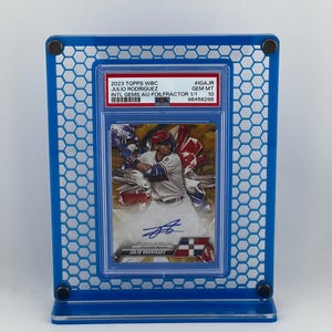 Puede incluir: Una tarjeta de b&eacute;isbol de Julio Rodr&iacute;guez, exhibida en un marco acr&iacute;lico azul. La tarjeta es de la serie 2023 Topps WBC, calificada como GEM MT 10. La tarjeta es una Intl Gems Au-Foilfractor 1/1.