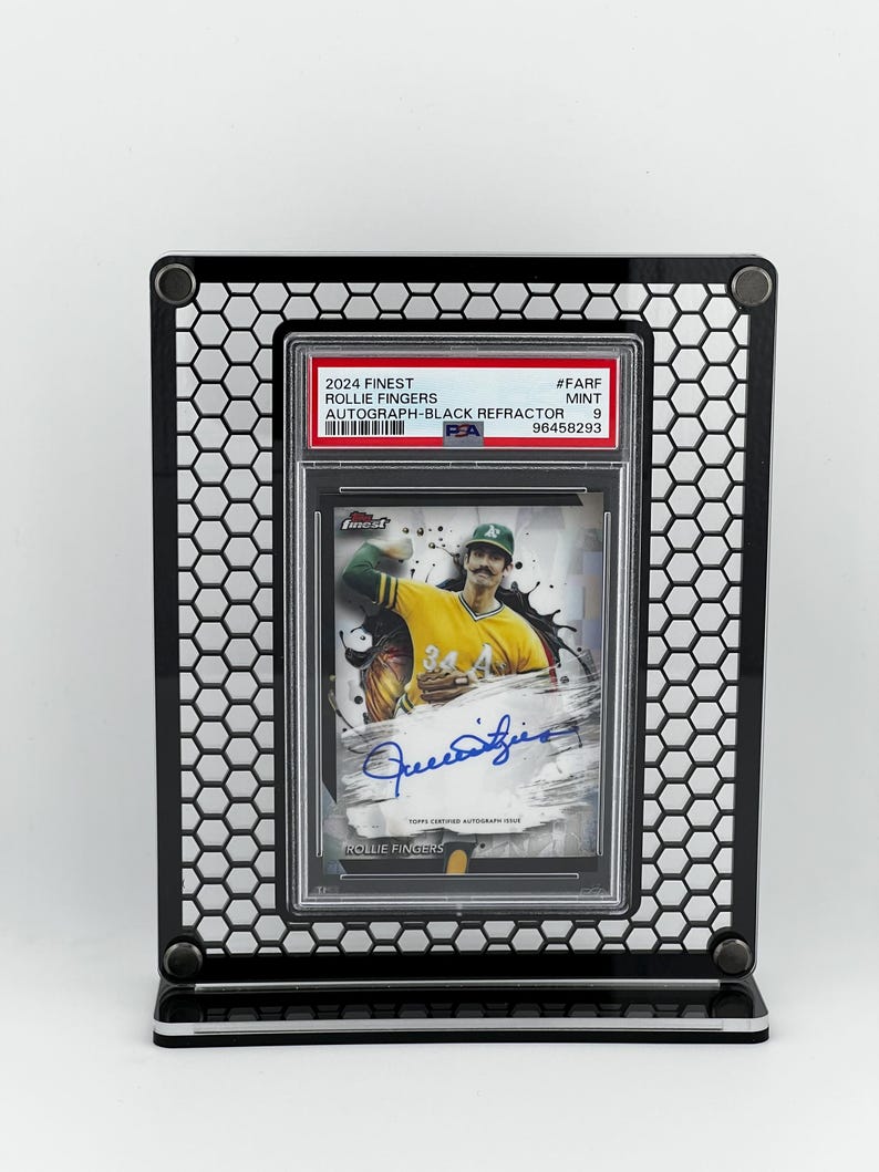 Puede incluir: Un soporte de exhibici&oacute;n negro que sostiene una tarjeta de b&eacute;isbol. La tarjeta presenta una imagen de Rollie Fingers con uniforme amarillo y verde, con su firma. La tarjeta est&aacute; etiquetada como "2024 Finest" y "Autograph-Black Refractor".