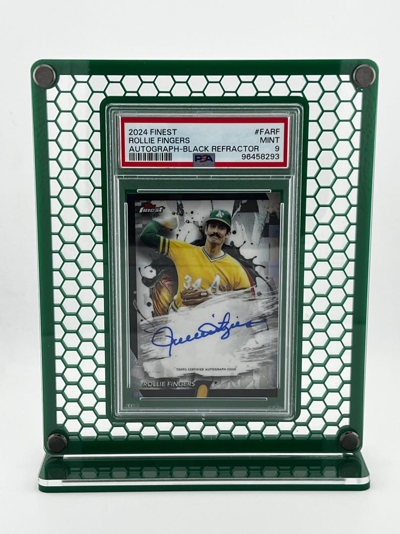 Puede incluir: Un marco de exhibici&oacute;n verde sostiene una tarjeta de b&eacute;isbol con Rollie Fingers. La tarjeta est&aacute; etiquetada como "2024 Finest Autograph-Black Refractor" e incluye el texto "TOPPS CERTIFIED AUTOGRAPH ISSUE". El marco tiene un patr&oacute;n de panal.