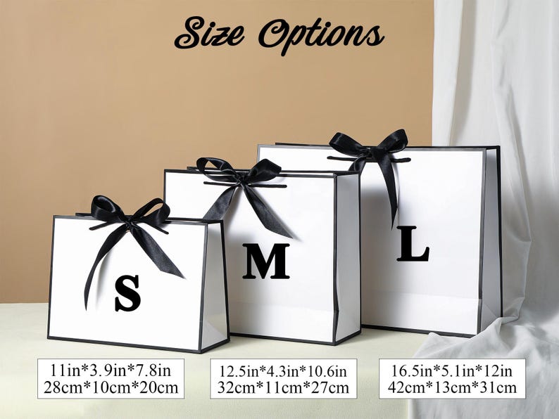 May include: Three white gift bags with black ribbon bows and black trim. The bags are labelled with the letters S, M, and L. The bags are 28 cm by 10 cm by 20 cm, 32 cm by 11 cm by 27 cm, and 42 cm by 13 cm by 31 cm.
