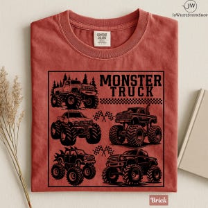 May include: Brick-colored t-shirt featuring a black graphic of four monster trucks with large tires. The text "MONSTER TRUCK" is above the trucks, with checkered flags and trees. The shirt is made of Comfort Colors material.