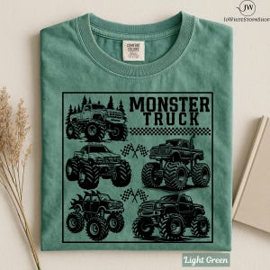 May include: Light green t-shirt featuring a black graphic of four monster trucks with large tires. The text "MONSTER TRUCK" is above the trucks. The shirt is made of Comfort Colors material.