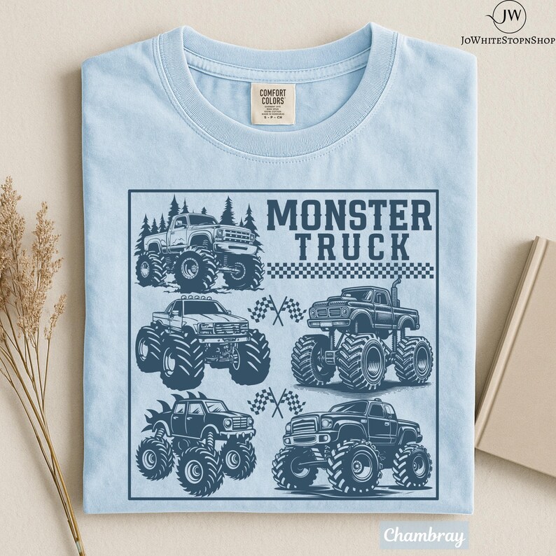 May include: Light blue t-shirt with a graphic of several monster trucks in a square frame. The words "MONSTER TRUCK" are printed in a bold font above the trucks. The shirt is made of a soft, comfortable material.
