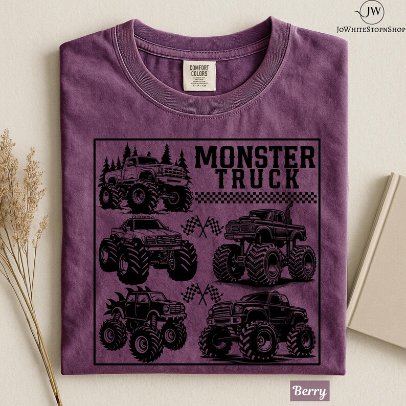 May include: Berry-colored t-shirt featuring a black graphic of several monster trucks. The text "MONSTER TRUCK" is displayed above the trucks. The shirt has a crew neck and short sleeves. The Comfort Colors tag is visible.