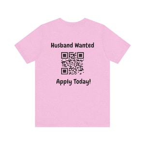May include: Pink t-shirt with the text "Husband Wanted" and a QR code. The text "Apply Today!" is below the QR code.