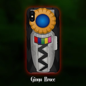 Puede incluir: Funda de teléfono negra con un diseño de Ginga Brace. Presenta un elemento circular dorado y azul, una sección central plateada con un patrón en zigzag y un detalle rectangular colorido. El texto "Ginga Brace" está en la parte inferior.