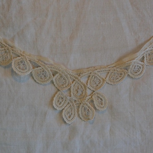 May include: White lace trim with a scalloped edge and a delicate floral pattern.