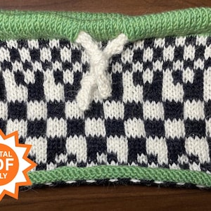 May include: Knitted cowl with a checkerboard pattern in black and white, accented with a green border and top. A white drawstring is visible at the top. The image includes a digital PDF only graphic.