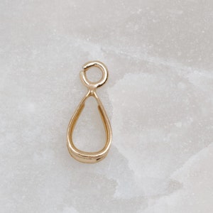 Puede incluir: Anilla de suspensión de oro en forma de lágrima, un bucle de metal para sujetar un colgante a una cadena o cordón.