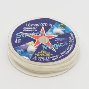 May include: A spool of clear elastic stretch magic beading cord. The label reads "Stretch Magic" and "1.8 mm/.070 in diameter" and "3 m 9 ft". The label also says "Bead & Jewelry Cord, Cuentas & Cordón de Bisutería, Strong & Stretchy/Resistant & Flexible, Cordón para Cuentas & Joyería Flexible".