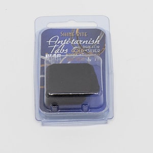 以下が含まれることがあります： 古い銀に最適なShine Rite Anti-Tarnish Tabsが入った透明なプラスチックパッケージ。パッケージは青い背景に白い文字と黒いタブが入っています。