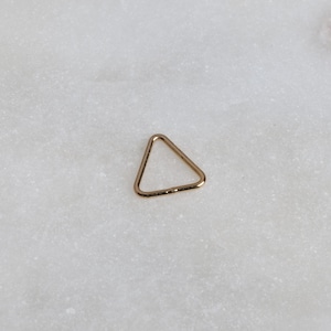 May include: A small gold triangle hoop earring.