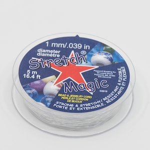 May include: A spool of clear elastic stretch magic bead and jewellery cord. The spool is labelled with the text "1 mm/.039 in diameter, 5 m 16.4 ft, Stretch Magic, Bead & Jewellery Cord Perle et Cordon de Bloude, Strong & Stretchy/Resistant & Flexible, Forte et Extensible/Resistante et Flexible, ©2019".