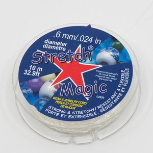 Puede incluir: Un carrete de cordón elástico mágico blanco para cuentas y joyería. La etiqueta dice 0,6 mm/0,024 pulgadas de diámetro, Stretch Magic, 10 m, 32,9 pies, Cordón para cuentas y joyería, Perle et Cordon de Bijoux, Fuerte y elástico/Resistente, Forte et Extensible, Resistante, y 02020.