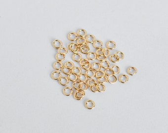 May include: A pile of small, gold jump rings. These rings are used for jewelry making and crafting.