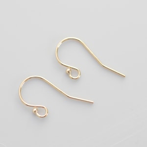 May include: Two gold-toned earring hooks with a small ball at the top of each hook.