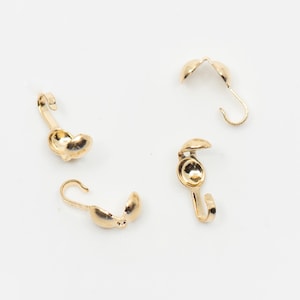 May include: Four gold-toned metal clasps with a hook on one end and a small, round, open-ended cap on the other end.