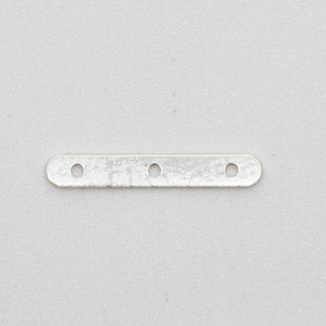 May include: A silver metal strip with three evenly spaced holes.