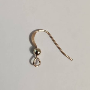 Peut inclure: Un crochet de boucle d'oreille doré avec une petite boule en haut.