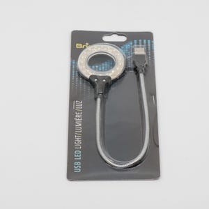 May include: A black and silver USB LED ring light with a flexible gooseneck. The light is packaged on a black card with the text "USB LED LIGHT/ LUMIÈRE/ LUZ".