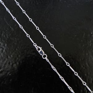 May include: A silver chain necklace with a delicate, elongated link design. The chain is approximately 18 inches long and features a lobster clasp closure.