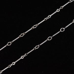 May include: A silver chain necklace with a simple, delicate design. The chain is made up of alternating long and short links.