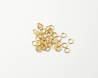 Könnte beinhalten: Ein Haufen goldener Sprungringe, eine Art von Schmuckzubehör, das zum Verbinden von Ketten, Schnüren und anderen Schmuckkomponenten verwendet wird.