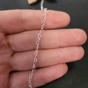 Pode incluir: Um colar de corrente de prata em forma de cora&ccedil;&atilde;o. A corrente &eacute; feita de pequenos elos em forma de cora&ccedil;&atilde;o interconectados.