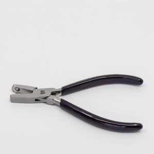 May include: A pair of silver-toned pliers with black rubber handles. The pliers have a rounded jaw on one side and a flat jaw on the other.