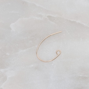 May include: A gold-toned hoop earring with a curved shape and a small hook closure.