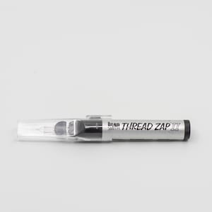 Może przedstawiać: Srebrno-czarne narzędzie Bead Smith Thread Zap II z przezroczystą plastikową nasadką. Na boku narzędzia znajduje się napis "THREAD ZAP II". Narzędzie jest przeznaczone do rękodzieła i tworzenia biżuterii.