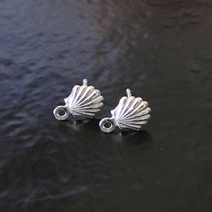 May include: A pair of silver shell-shaped earring findings with a small loop on the side.