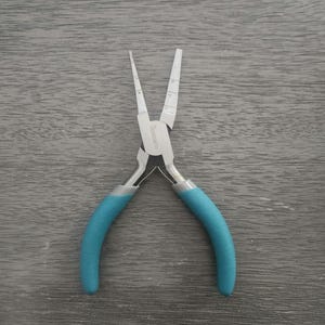 May include: A pair of blue handled pliers with a silver metal body. The pliers have a small measurement scale on the side.