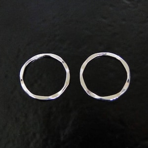 May include: Two silver, textured, open hoop earrings. The earrings are simple and elegant.
