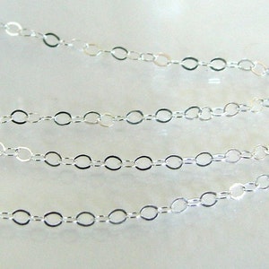 May include: A silver chain with oval links. The chain is laid out in a straight line with three rows of links.