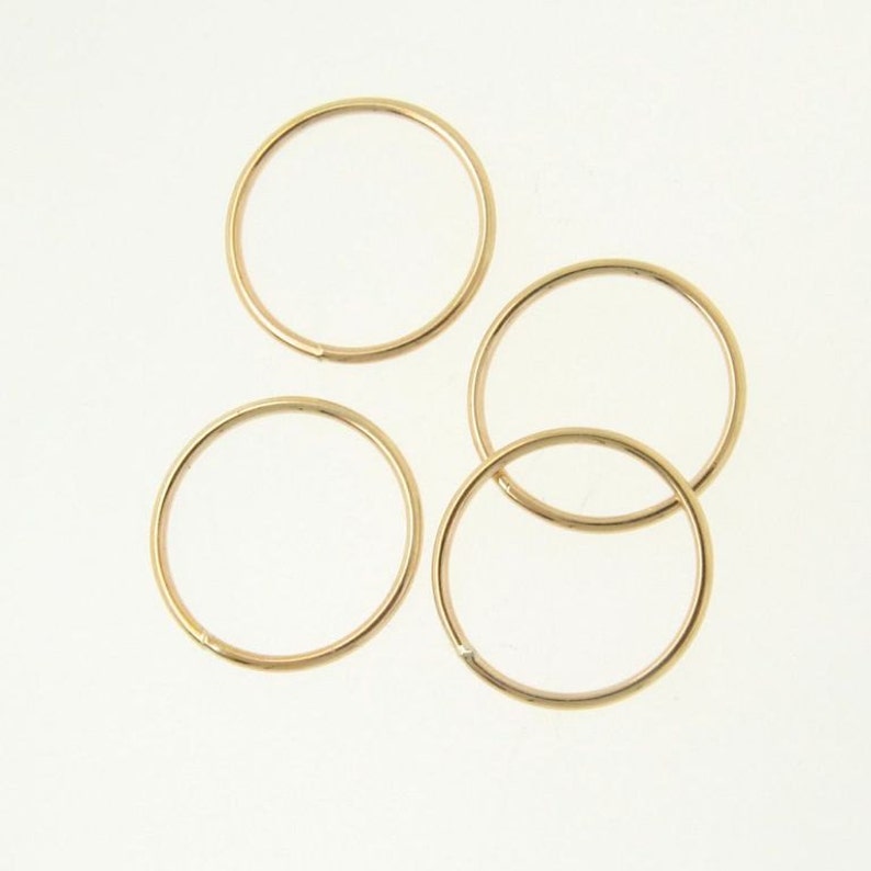 May include: Four gold-colored hoop earrings. The hoops are all the same size and are arranged in a semi-circle.