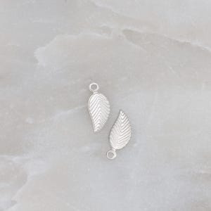May include: Two silver leaf charms with a loop at the top for attaching to jewelry or other crafts.