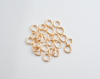 Könnte beinhalten: Ein Haufen von 20 goldenen Sprungringen, eine Art von Schmuckzubehör, das zum Verbinden von Ketten, Schnüren und anderen Schmuckkomponenten verwendet wird.