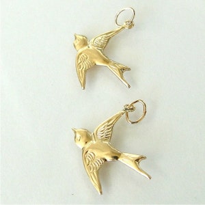 May include: Two gold-colored swallow bird charms with a loop for attaching to a necklace or bracelet.